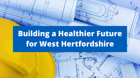 Picture of a set of blue plans on top of which is a yellow hard hat. The text says: Building a Healthier future for West Hertfordshire
